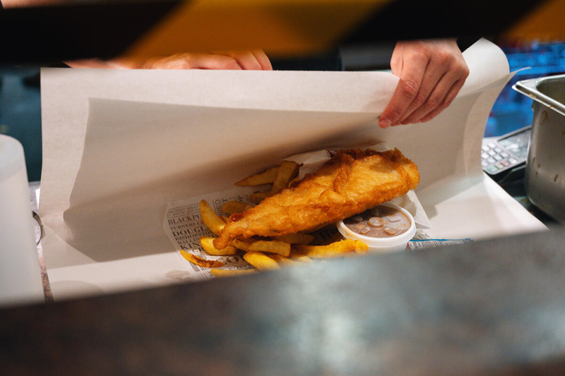 A freshly prepared fish and chips meal being wrapped in paper at a takeaway in Kinsale, County Cork.