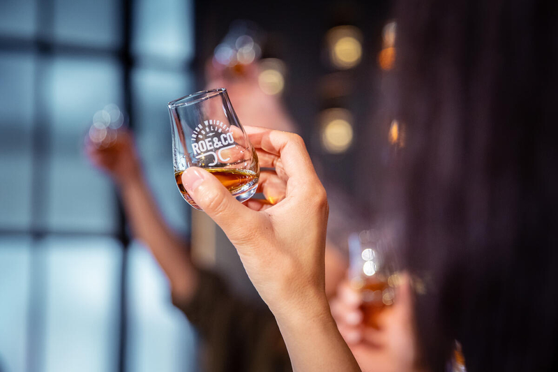 Hand holding a Roe & Co whiskey glass during a guided tasting at the Roe & Co Distillery in Dublin.